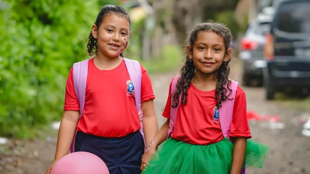Two girls in red shirts with their new pink backpacks